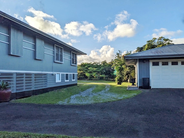 view of yard with a garage and aphalt driveway