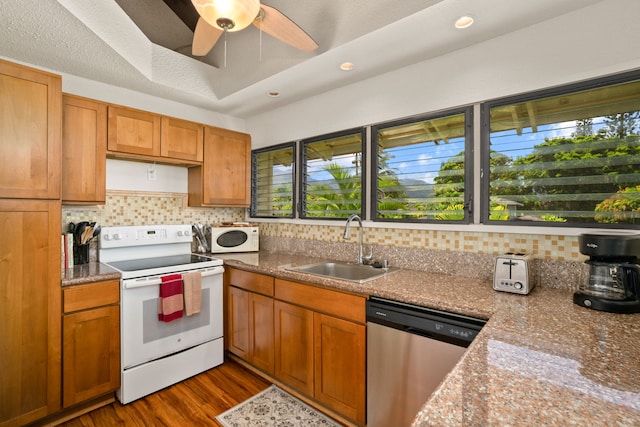 kitchen with sink, dark hardwood / wood-style flooring, a raised ceiling, white appliances, and light stone countertops