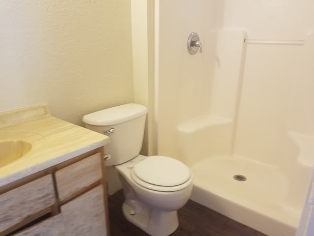 bathroom featuring vanity, wood-type flooring, toilet, and walk in shower