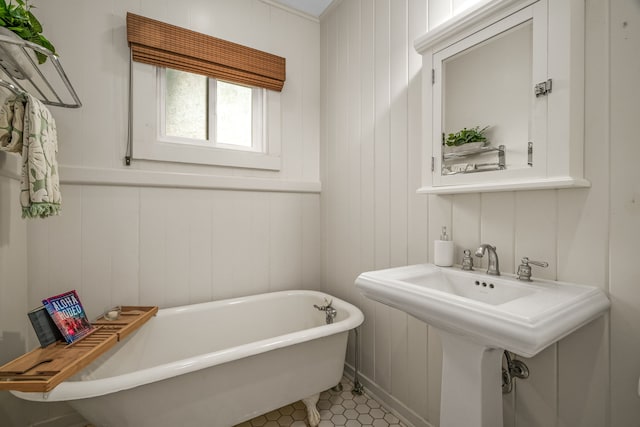 full bathroom with a soaking tub, a decorative wall, and a sink