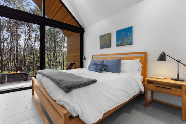 bedroom featuring light tile patterned flooring, wooden walls, and high vaulted ceiling