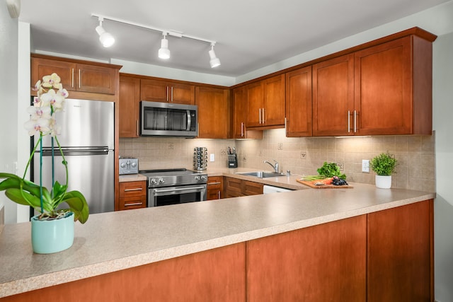 kitchen featuring appliances with stainless steel finishes, tasteful backsplash, track lighting, and sink