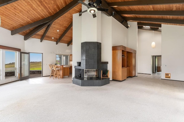 living room featuring high vaulted ceiling, beamed ceiling, a wood stove, wood ceiling, and light carpet