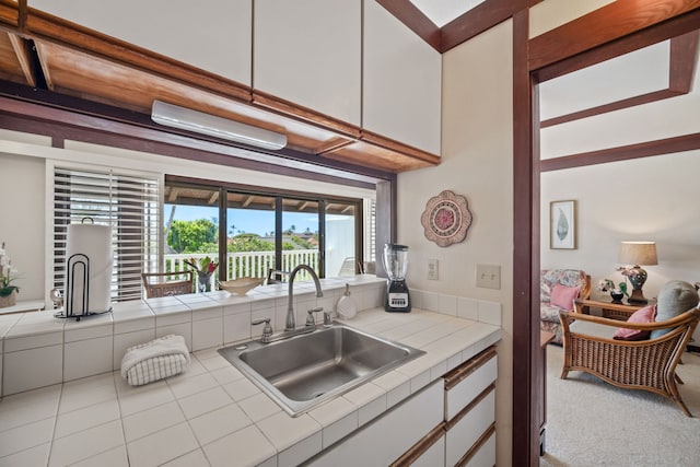 kitchen featuring white cabinets, tile countertops, and sink