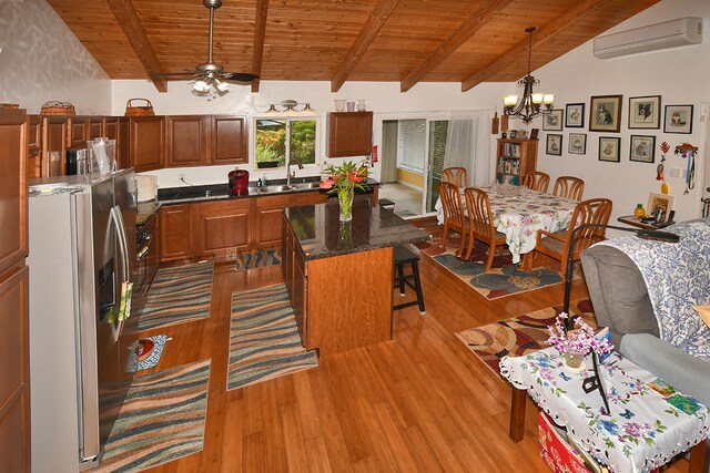 kitchen featuring hanging light fixtures, a kitchen island, stainless steel refrigerator with ice dispenser, hardwood / wood-style floors, and an AC wall unit