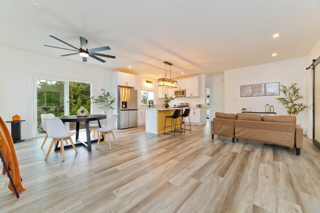 living room featuring a barn door, ceiling fan, and light hardwood / wood-style floors