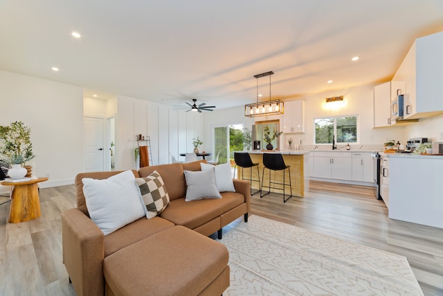 living room with ceiling fan, sink, and light hardwood / wood-style floors