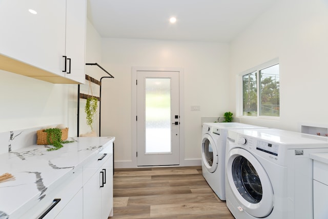 laundry room featuring cabinets, light hardwood / wood-style floors, and independent washer and dryer