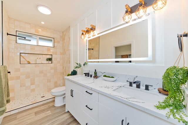 bathroom featuring tiled shower, toilet, vanity, and hardwood / wood-style flooring