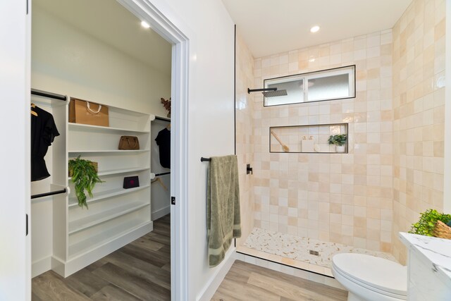 bathroom featuring hardwood / wood-style flooring, toilet, and tiled shower