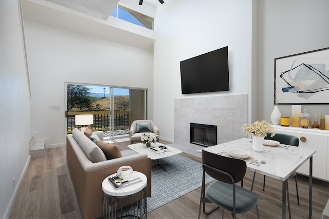 living room featuring wood-type flooring, a fireplace, and a high ceiling