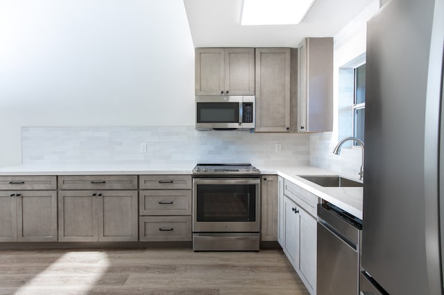 kitchen featuring appliances with stainless steel finishes, sink, decorative backsplash, and light hardwood / wood-style flooring