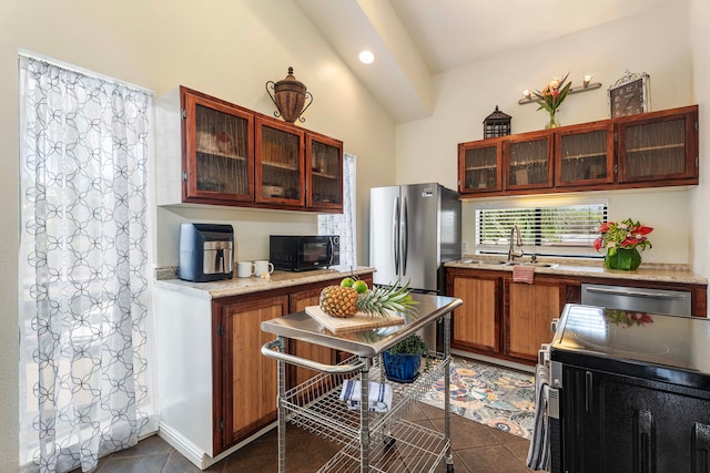 kitchen with range, stainless steel refrigerator, sink, and dark tile patterned floors