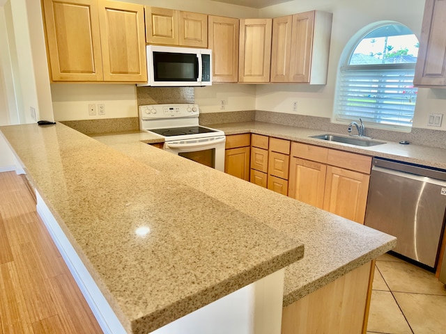 kitchen featuring light brown cabinetry, stainless steel dishwasher, sink, and white range with electric stovetop