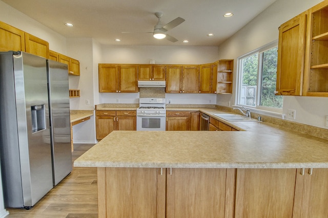 kitchen featuring ceiling fan, sink, kitchen peninsula, appliances with stainless steel finishes, and light wood-type flooring