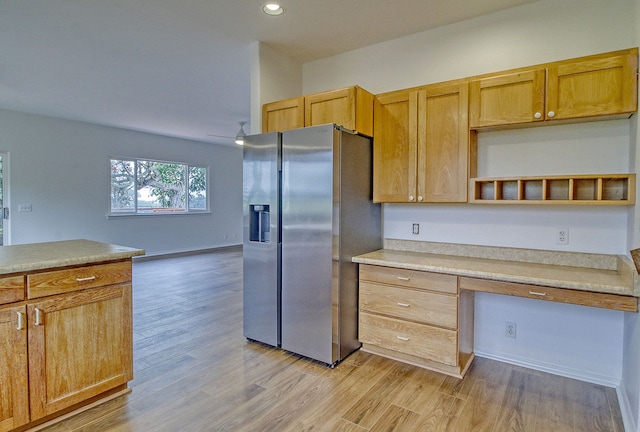 kitchen with light wood-type flooring, stainless steel fridge with ice dispenser, and built in desk