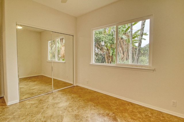 unfurnished bedroom with a closet, multiple windows, and ceiling fan