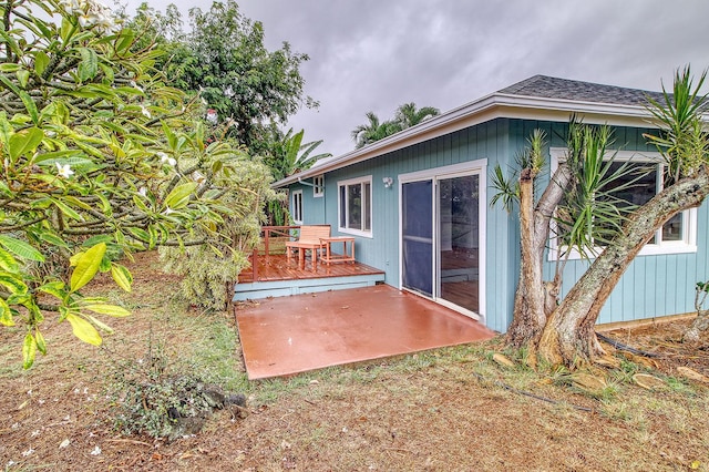rear view of house featuring a wooden deck and a patio area