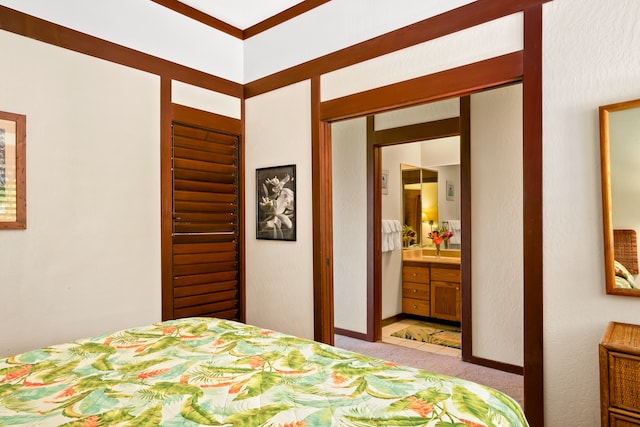 bedroom featuring light colored carpet, crown molding, and ensuite bathroom