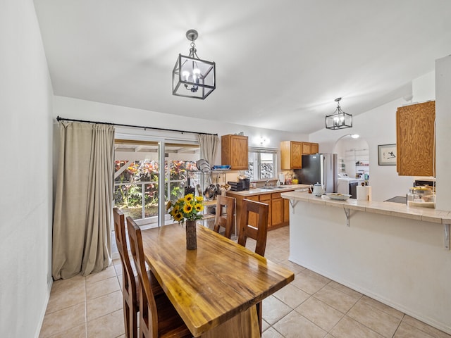 dining room with lofted ceiling, a chandelier, light tile patterned floors, and sink