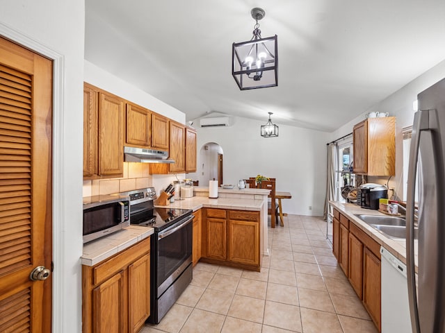 kitchen with lofted ceiling, sink, kitchen peninsula, appliances with stainless steel finishes, and decorative light fixtures