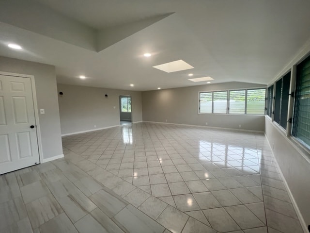 spare room featuring a skylight, plenty of natural light, and light tile patterned flooring