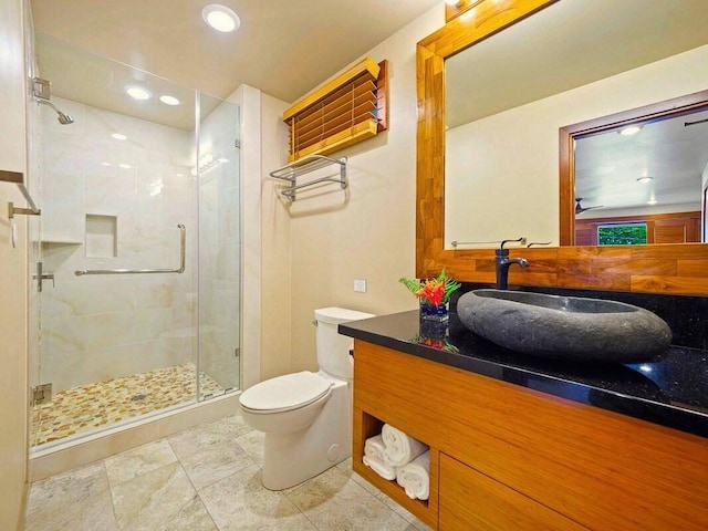 bathroom with tile patterned flooring, a shower with shower door, vanity, and toilet