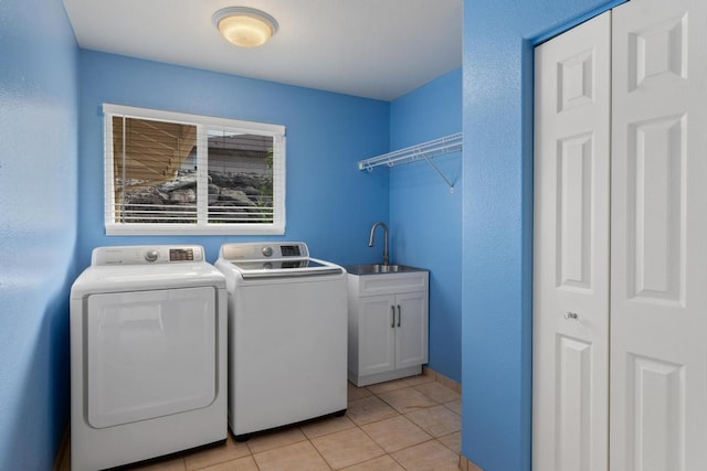 laundry area featuring sink, light tile patterned flooring, washing machine and dryer, and cabinets