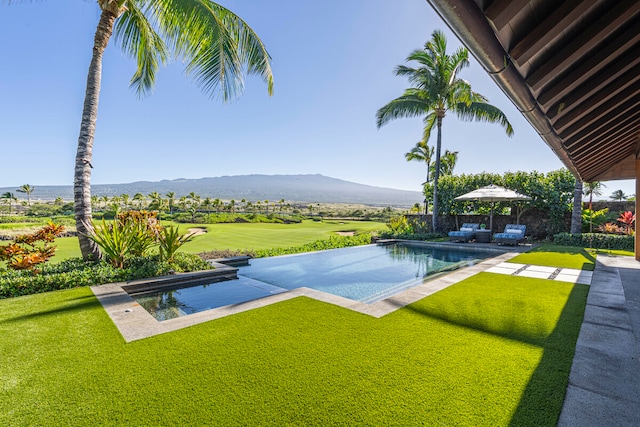 view of pool featuring a yard, a mountain view, and a patio area