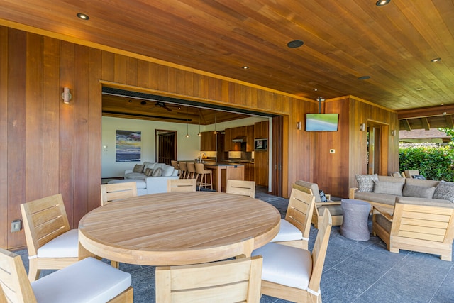 dining area featuring wood ceiling and wood walls