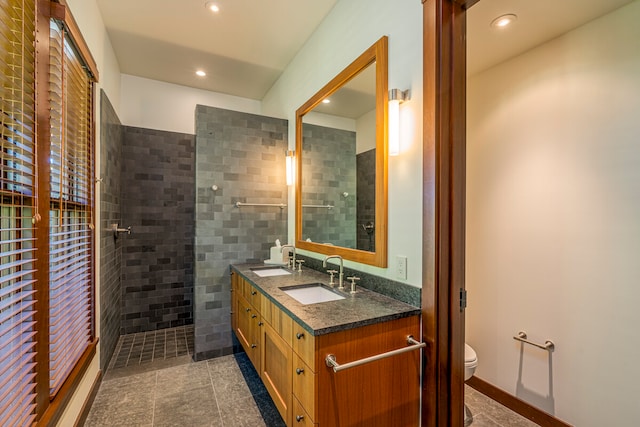 bathroom featuring a tile shower, tile walls, tile patterned flooring, vanity, and toilet