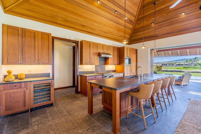 kitchen featuring wood ceiling, high vaulted ceiling, pendant lighting, a center island with sink, and sink