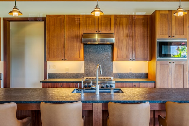 kitchen with a kitchen bar, hanging light fixtures, and sink