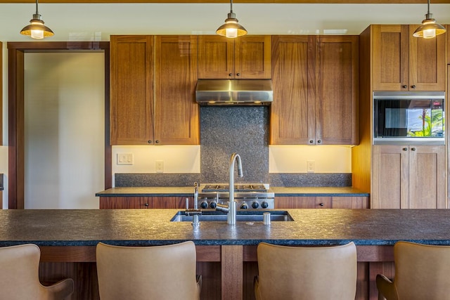 73-4839 Maia Loop Unit 40, Kailua-Kona, HI 96740 - kitchen featuring under cabinet range hood, a sink, dark countertops, and pendant lighting