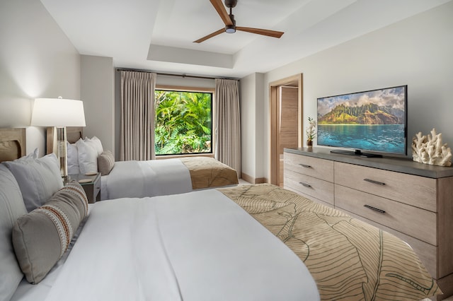 bedroom with ceiling fan and a raised ceiling