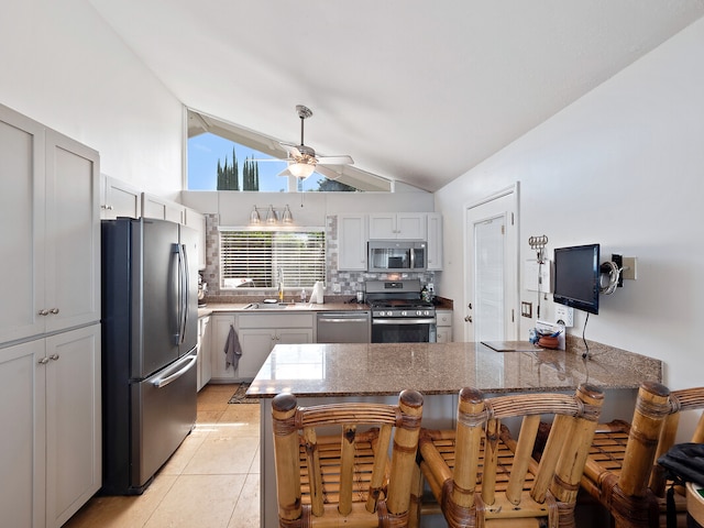 kitchen featuring ceiling fan, stainless steel appliances, a kitchen bar, and kitchen peninsula