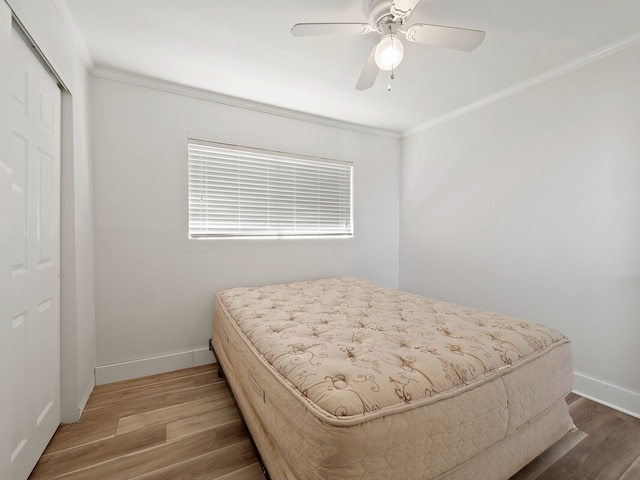 bedroom featuring ornamental molding, a closet, hardwood / wood-style floors, and ceiling fan