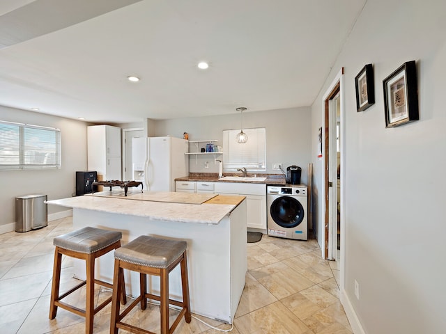 kitchen featuring washer / clothes dryer, hanging light fixtures, sink, white refrigerator with ice dispenser, and white cabinets