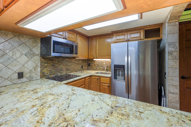 kitchen featuring light stone countertops, stainless steel appliances, sink, and tasteful backsplash