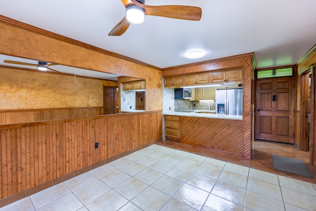 kitchen with wood walls, kitchen peninsula, stainless steel appliances, crown molding, and decorative backsplash