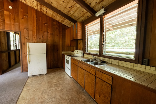 kitchen with white appliances, wood walls, tile countertops, vaulted ceiling with beams, and sink