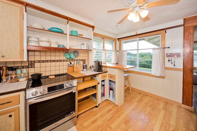 kitchen featuring tasteful backsplash, light wood-type flooring, ceiling fan, tile counters, and stainless steel stove