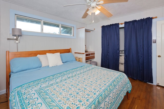 bedroom featuring dark wood-type flooring, ceiling fan, wood walls, and a textured ceiling