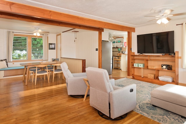 living room with light hardwood / wood-style floors, beam ceiling, and ceiling fan