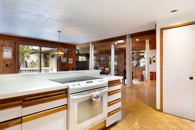 kitchen featuring wood walls, white electric stove, a textured ceiling, and hanging light fixtures