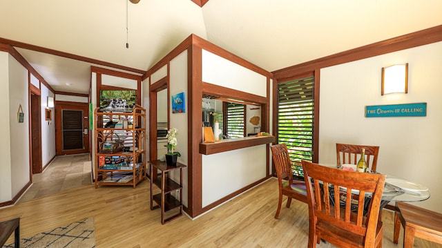 dining area featuring light hardwood / wood-style flooring, crown molding, and vaulted ceiling