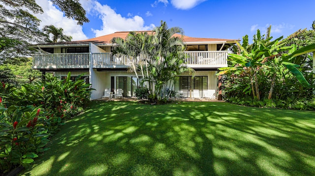 back of house with a balcony and a lawn