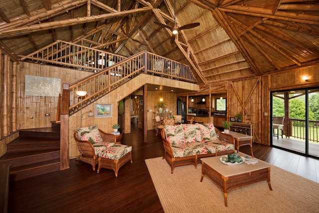 living room featuring wood walls, dark wood-type flooring, high vaulted ceiling, and beamed ceiling