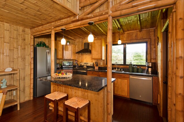 kitchen featuring pendant lighting, wall chimney range hood, a center island, and stainless steel appliances