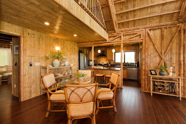 dining room featuring dark wood-type flooring, wood walls, and wooden ceiling